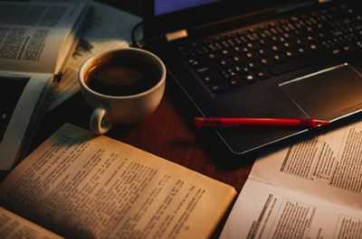książki, laptop, kubek z kawą i długopis