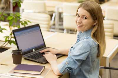 Kobieta pracująca przy komputerze i uśmiechająca się